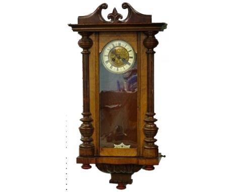 A Vienna wall clock, in a walnut case, the enamel type dial with pressed decoration of a angels, scrolls etc., enclosed withi