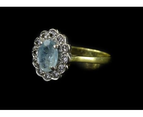 An 18ct gold aquamarine and diamond cluster ring, with central oval cut aquamarine in claw setting, and tiny illusion set dia