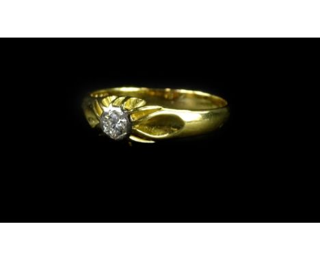 An 18ct gold diamond solitaire ring, the diamond in platinum rub over setting, with raised and waved design ring head, on a p