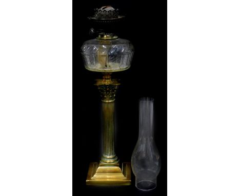 A late 19th/early 20thC corinthian column brass oil lamp, with a clear reservoir, on square base, 78cm H including chimney.