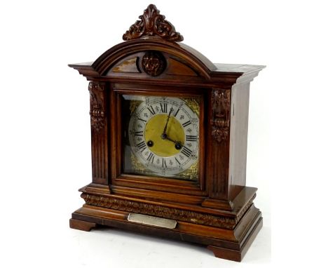 A German mantel clock, in a walnut case, the crest decorated with a lion mask above a squared dial, with silver chaptering, a