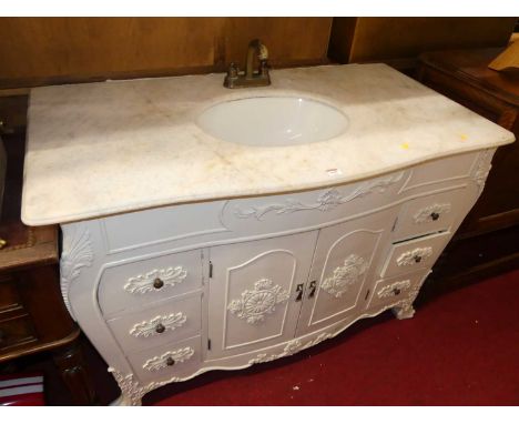A contemporary French style vanity unit, the quartz top surface with integral basin and brass taps, on white painted floral d