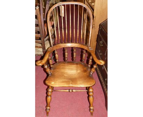 An elm, beech and fruit wood comb back Windsor chair, raised on turned supports to H-stretcher, width 68cm