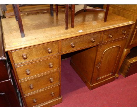 A Victorian oak round cornered kneehole writing desk, having an arrangement of six drawers and single arched panel cupboard d