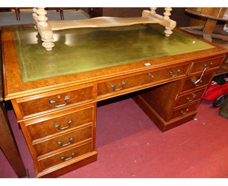 A reproduction burr walnut and gilt tooled green leather inset twin pedestal writing desk, having an arrangement of nine lock