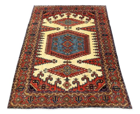 Persian rug carpet, cream ground field decorated with large red and blue central medallion and two lozenges, spandrels decora