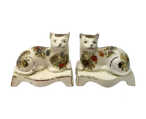Pair of 19th century Staffordshire cats, modelled in recumbent pose, upon bases with bracket feet, later decorated with trans