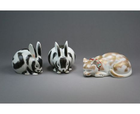 A pair of Japanese Kutani porcelain figures of rabbits Taisho period Modelled seated with heads down nibbling, decorated with