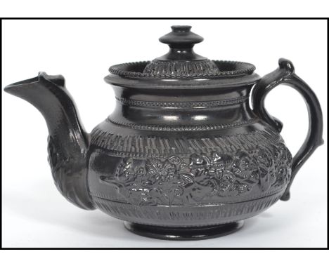A possibly Wedgwood 19th century Victorian black basalt caneware (cane wear) ceramic teapot of globular form being decorated 