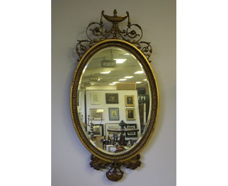 19th Century gilt framed oval wall mirror, with urn, swag and scrolled leaf cresting, bevelled mirror plate and conforming ap