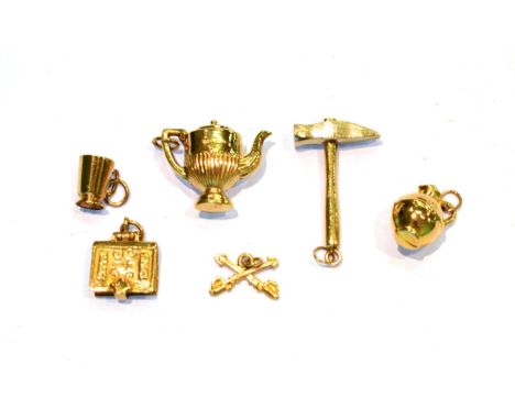 Four 9 carat gold charms including a hammer, a mug, a teapot and a bible; a kettle charm stamped '9CT'; and a pair of crossed