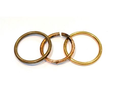 A silver bangle; a 9 carat gold bangle; and a bangle stamped '9CT' (a.f.) .  Silver bangle - 12.1 grams. Two other bangles - 