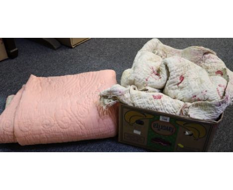 Two vintage quilts; one floral design and the other plain with pale yellow on one side and pink on the other. Together with a
