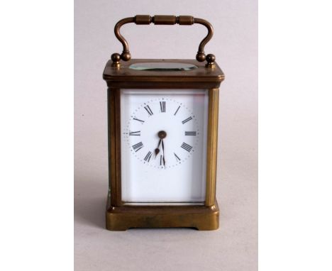 A French brass carriage clock, enamel dial with Roman numerals, the top with oval glass panel revealing workings, with four b