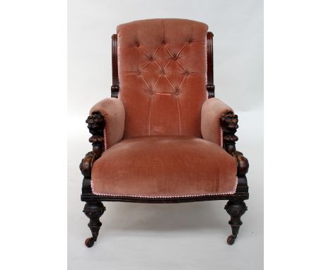 A Victorian mahogany button back gentleman's armchair, the arms carved with lion masks, over turned legs and castors
