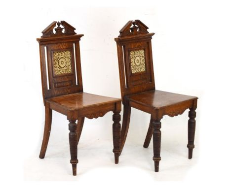 Pair of late 19th Century oak hall chairs having pediment cresting, the back inset with a brown and white transfer printed ti