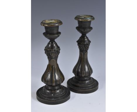 A pair of 19th century dark patinated bronze candlesticks, each cast with masks and lotus, 17cm high, c.1830