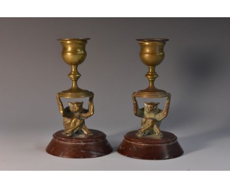 A pair of 19th century gilt bronze novelty candlesticks, each sconce held aloft by a monkey, detachable nozzles, circular rou