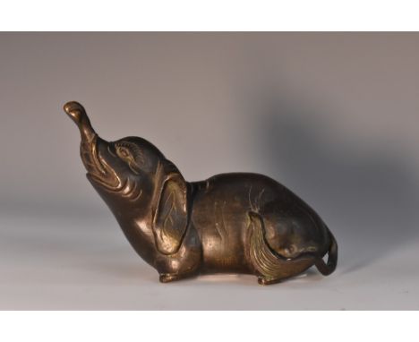 Indian School, a dark patinated bronze, of an elephant, the beast sits lifting its head and trunk upward, 7cm high, 11cm wide