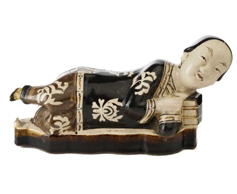 A Chinese Cizhou figural pillow, Song dynasty or later, modelled as a recumbent female, wearing a black jacket and light brow
