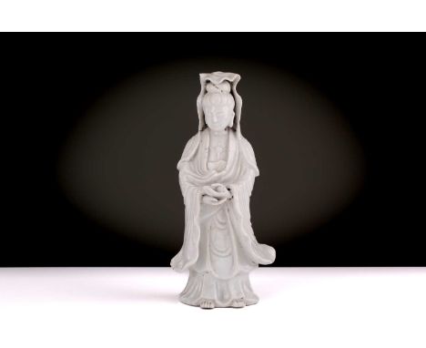 A Chinese Dehua blanc de chine standing figure of Guanyin, Qing dynasty, 198th century, in long flowing robes, holding a scro