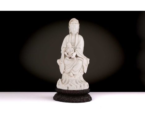 A Chinese Dehua blanc de chine figure of Guanyin, Qing dynasty, Kangxi,17th century, seated in lalitasana, a child seated on 