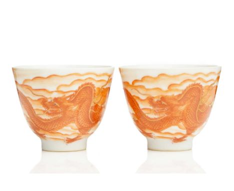 A pair of Chinese porcelain iron red wine cups, painted with a dragon with partial gilt outline amongst clouds, apocryphal fo