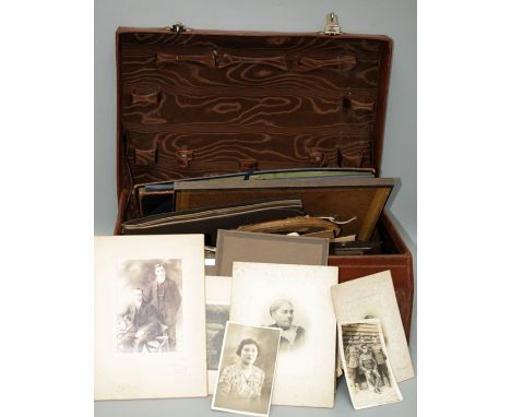 An early 20th century stitched leather vanity case containing many dozens of largely early 20th century studio portrait and o