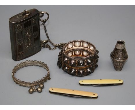 An Omani white metal box with floral panel decoration suspended from a chain, an Omani bi-coloured studded bangle, a filigree
