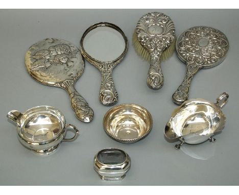 Three silver backed hand mirrors (one glass deficient), a silver brush, sauce boat, a pedestal cream, salt , souvenir spoon a