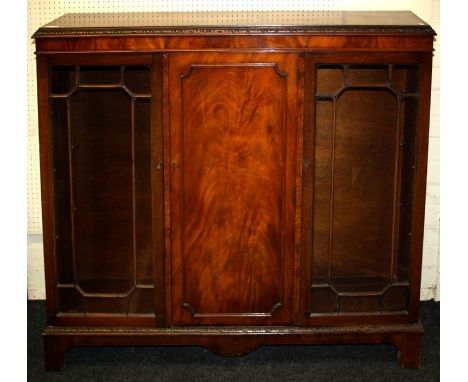 A reproduction mahogany bookcase cabinet, the rectangular top over panel cupboard door flanked by astragal glazed doors on br