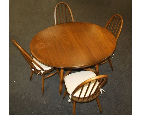 An Ercol elm dining table, the oval top with twin flaps on splayed supports united by cross stretcher, together with a set of