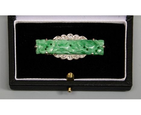 An Art Deco jade and diamond set brooch, comprising a rectangular carved jade with a scalloped edge set with old cut diamonds