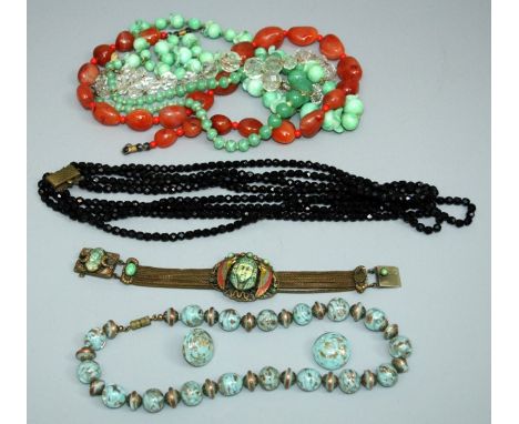 An early 20th century Egyptian Revival bracelet set with winged enamel carved hardstone mask on a gilt multi strand strap wit