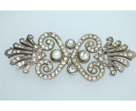 An early 20th century German white metal cloak clip cape clasp in a rococo design set with paste stones. Measures 7cms