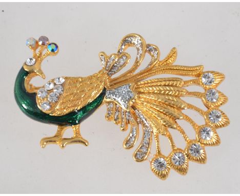 A vintage yellow metal enamelled figural brooch in the form of a peacock with with rhinestone and glitter decoration and roll
