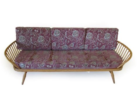 A 1960's Beech and Elm Studio Couch, with oval panel back support and spindle arm supports on splayed legs, with later recove