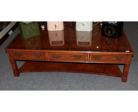 A reproduction burr walnut and crossbanded rectangular coffee table, with six small drawers and square legs joined by a shelf