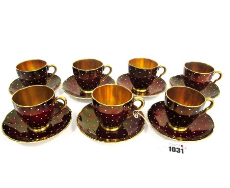 A Carlton Ware Pottery Part Coffee Service, the dark red grounds decorated with white enamel dots, the cups with gilt interio