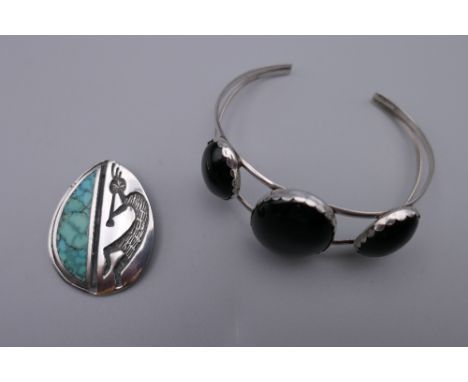 A silver and three stone onyx Navajo bangle and a Navajo silver and turquoise pendant with musician design. The former 5.5 cm