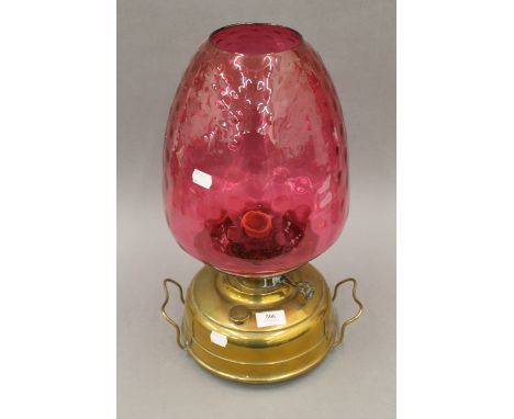 A Victorian brass oil lamp with cranberry shade. 45 cm high.