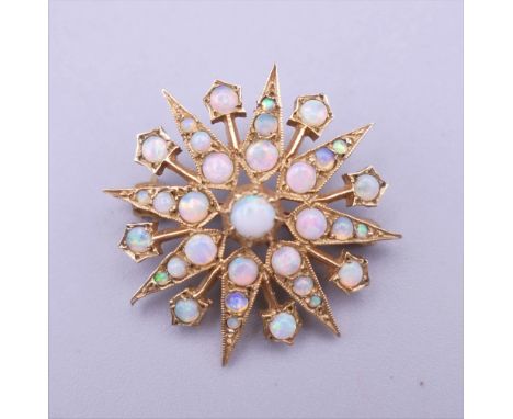 A 9 ct gold opal set starburst form pendant/brooch. 2.75 cm wide. 5.4 grammes total weight.