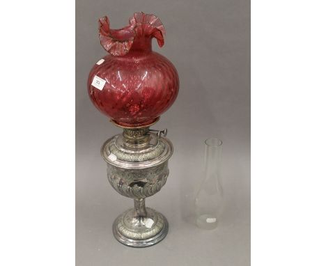 A Victorian silver plated oil lamp and cranberry glass shade. 56 cm high.