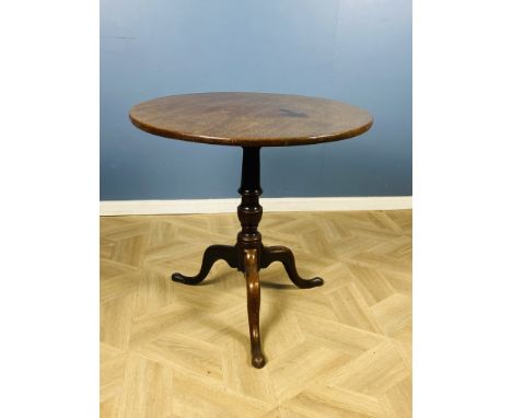 A Georgian mahogany tilt top tripod table, raised upon a turned central column with shaped legs and pad feet, 70cms top diame