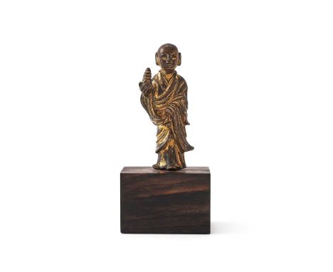 A rare Chinese gilt-bronze figure of a Lohan, Tang dynasty (8th century), standing in folded robes and his right hand holding