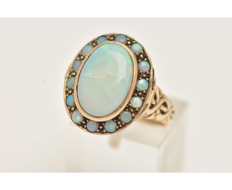 A YELLOW METAL OPAL LOCKET RING, a large AF oval opal collet set in yellow metal, set with a surround of circular opals, fitt