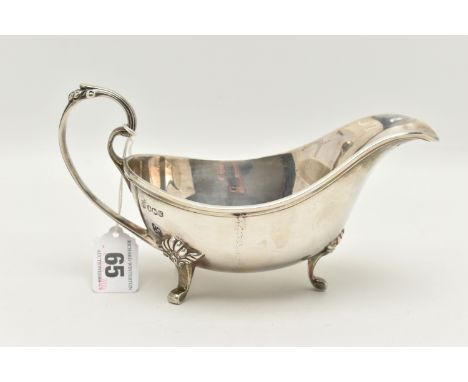 AN ELIZABETH II SILVER GRAVY BOAT, polished form with scroll handle and shell detailed thumb rest, raised on three cabriole l