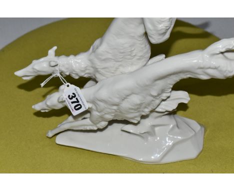 A  HUTSCHENREUTHER WHITE PORCELAIN MODEL OF TWO BORZOI DOGS LEAPING OVER A ROCKY OUTCROP, designed by Karl Tutter, green back