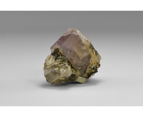 A semi-transparent, blocky, lavender apatite crystal with several smaller apatite crystals, and with accessory specular hemat