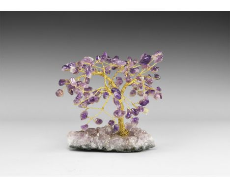 A medium size gemstone tree consisting of a brass trunk and branches tipped with polished amethysts, mounted on a section of 